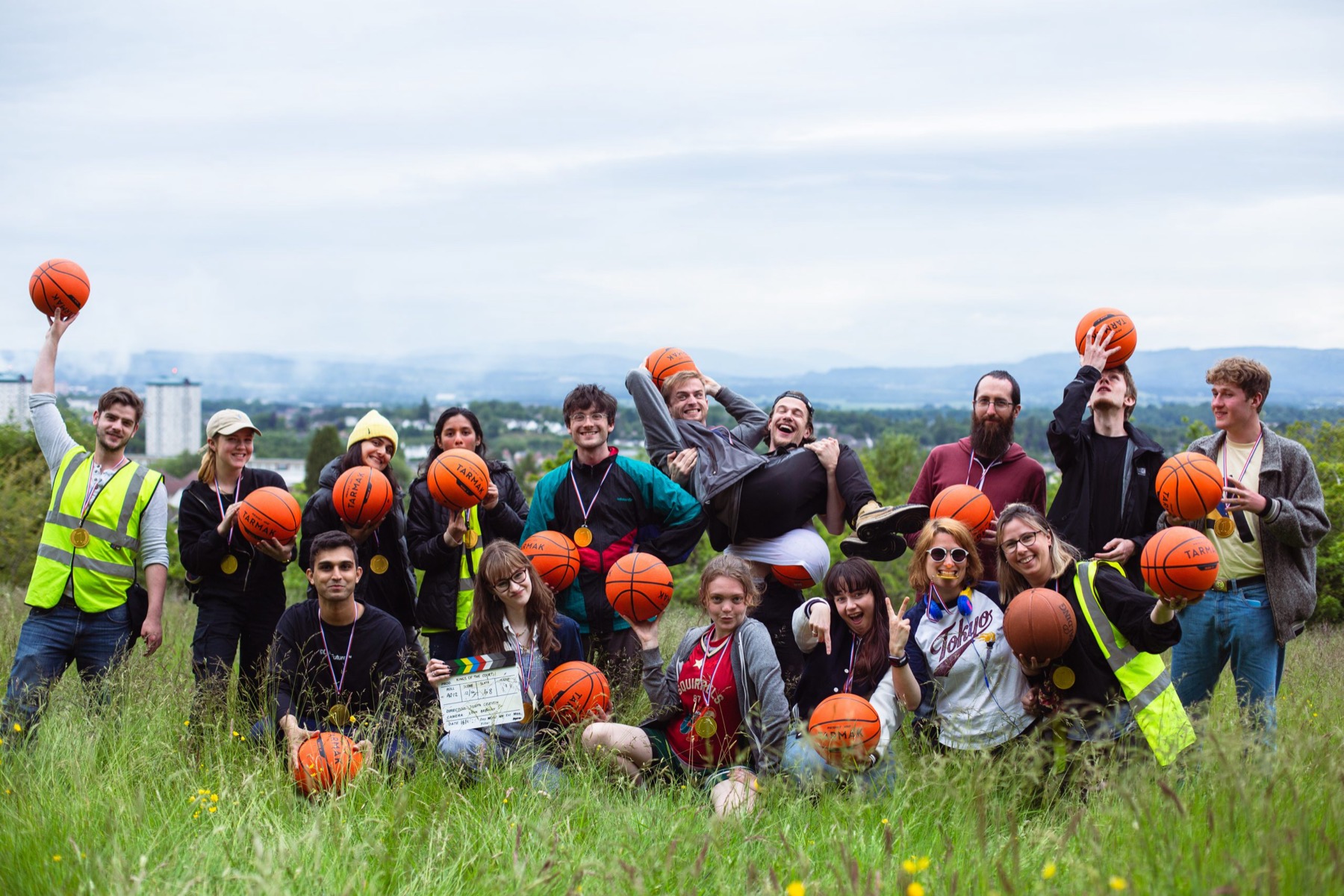 The Kings of the Court cast and crew in a grassy field, holding basketballs and cheering